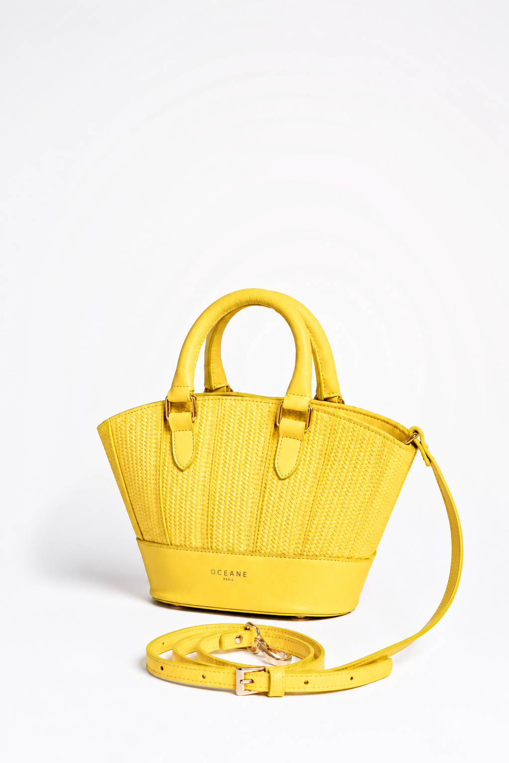Jade Bag gialla di Oceane Paris, vista di tre quarti con due manici e tracolla appoggiata accanto alla borsa.