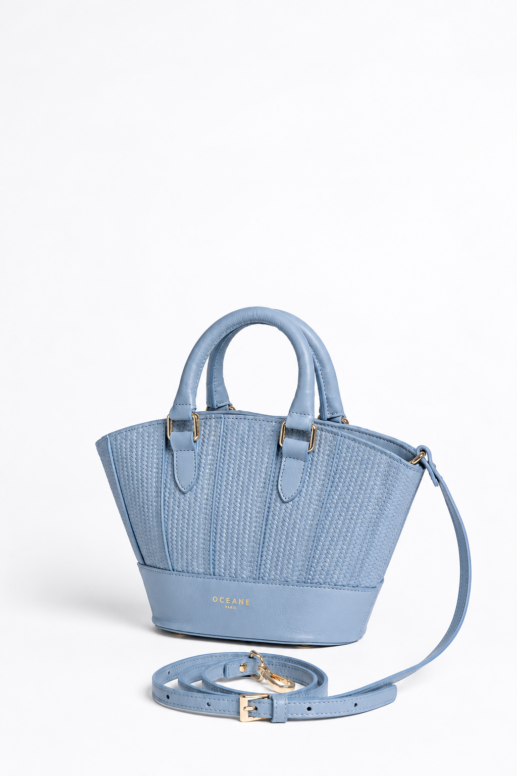 Jade Bag azzurra di Oceane Paris, vista di tre quarti con due manici e tracolla appoggiata accanto alla borsa.