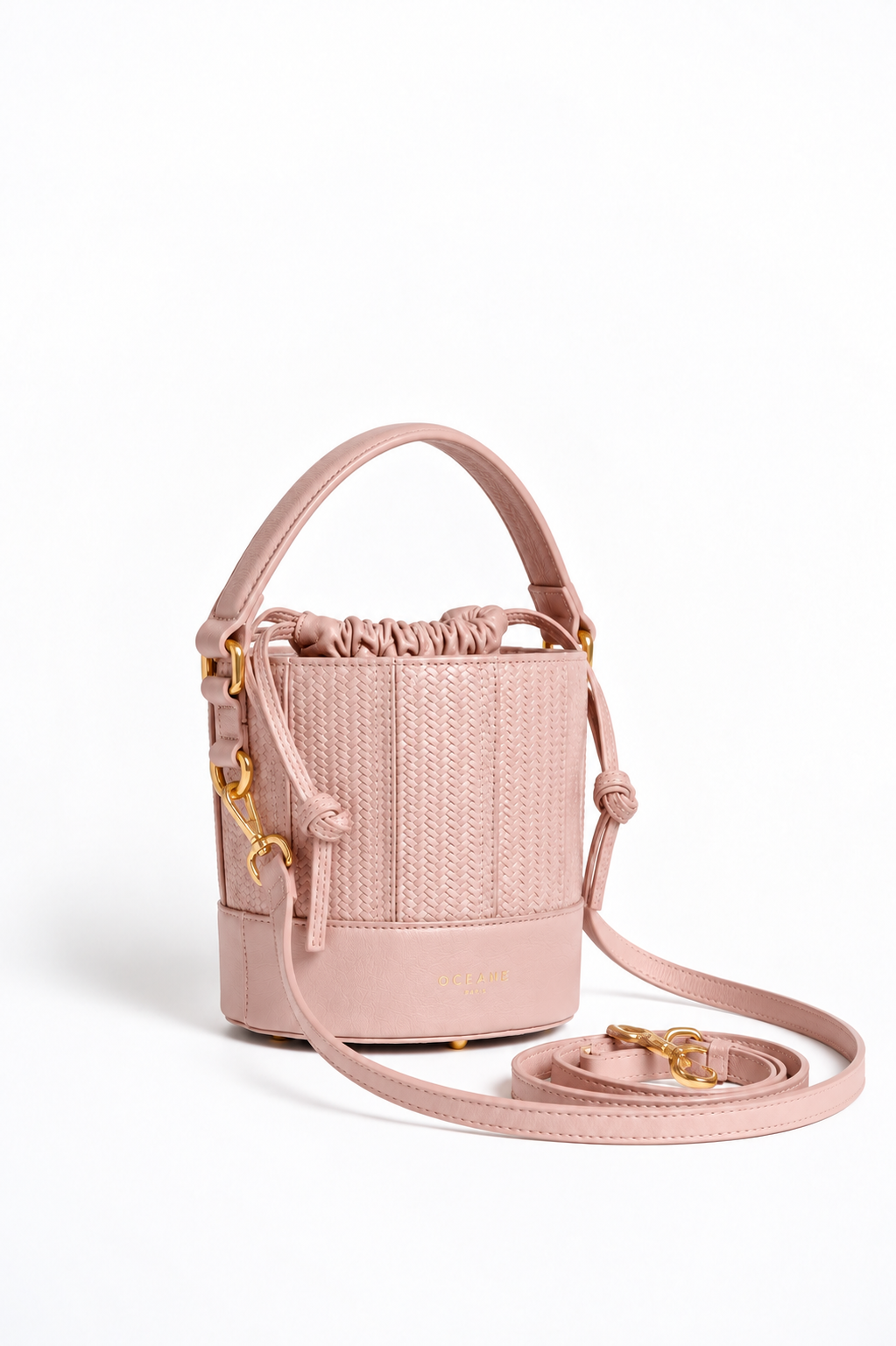Grace Bucket rosa cipria di Oceane Paris, vista di tre quarti con manico in pelle, tracolla e dettagli dorati.
