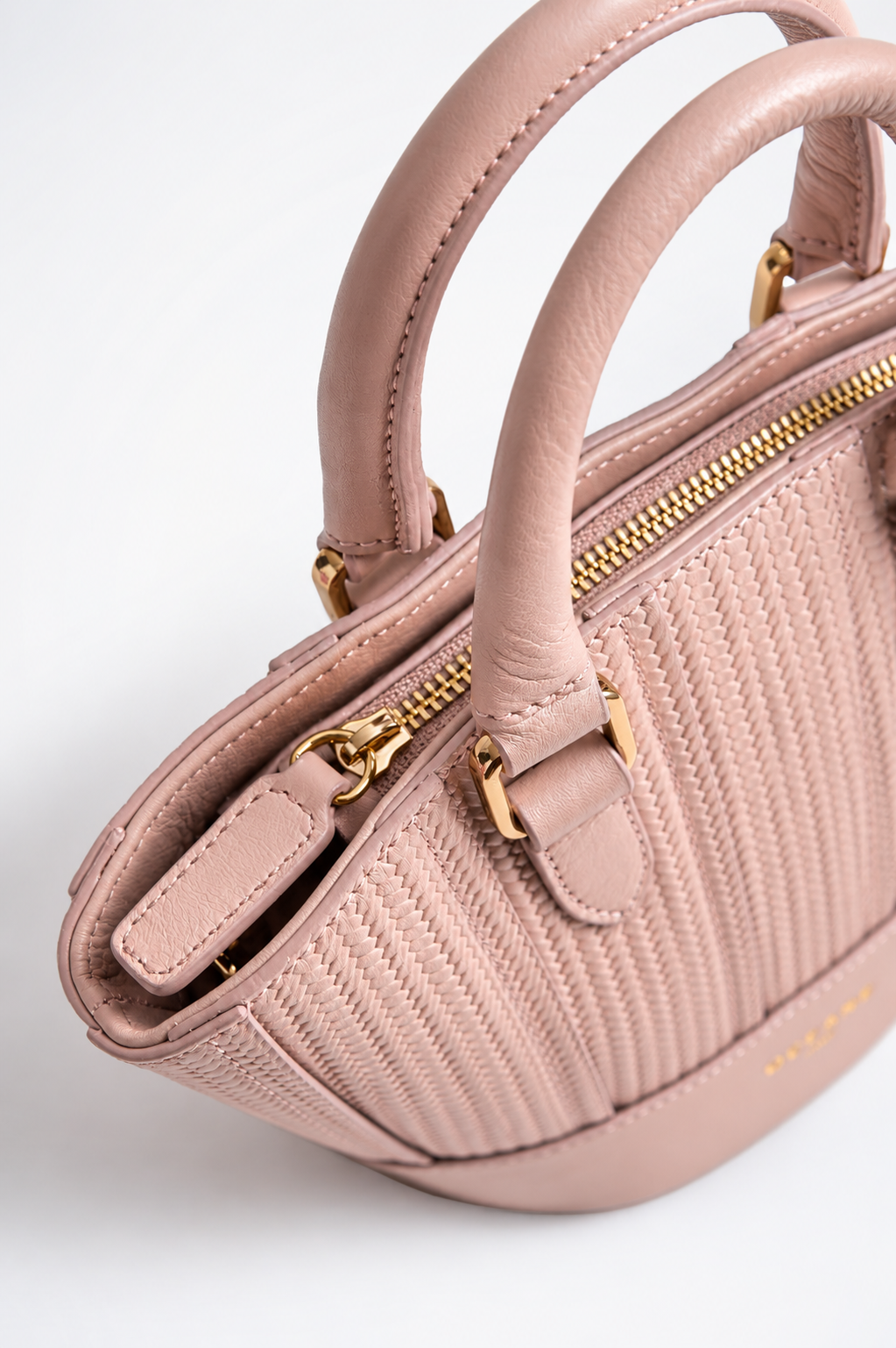Dettaglio della Jade Bag rosa cipria di Oceane Paris, con manici in pelle, zip dorata e lavorazione intrecciata.